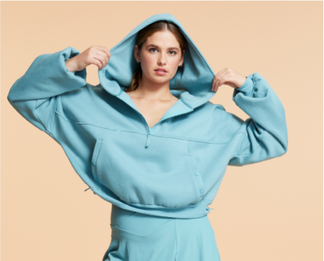 A model wearing the teal blue Blogilates Marshmallow Half Zip Hooded Sweatshirt.