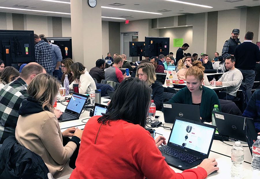 A large group of team members sitting in the holiday command center monitoring laptops and large screens