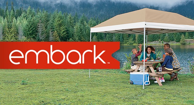 a group of people sitting at a picnic table by a lake