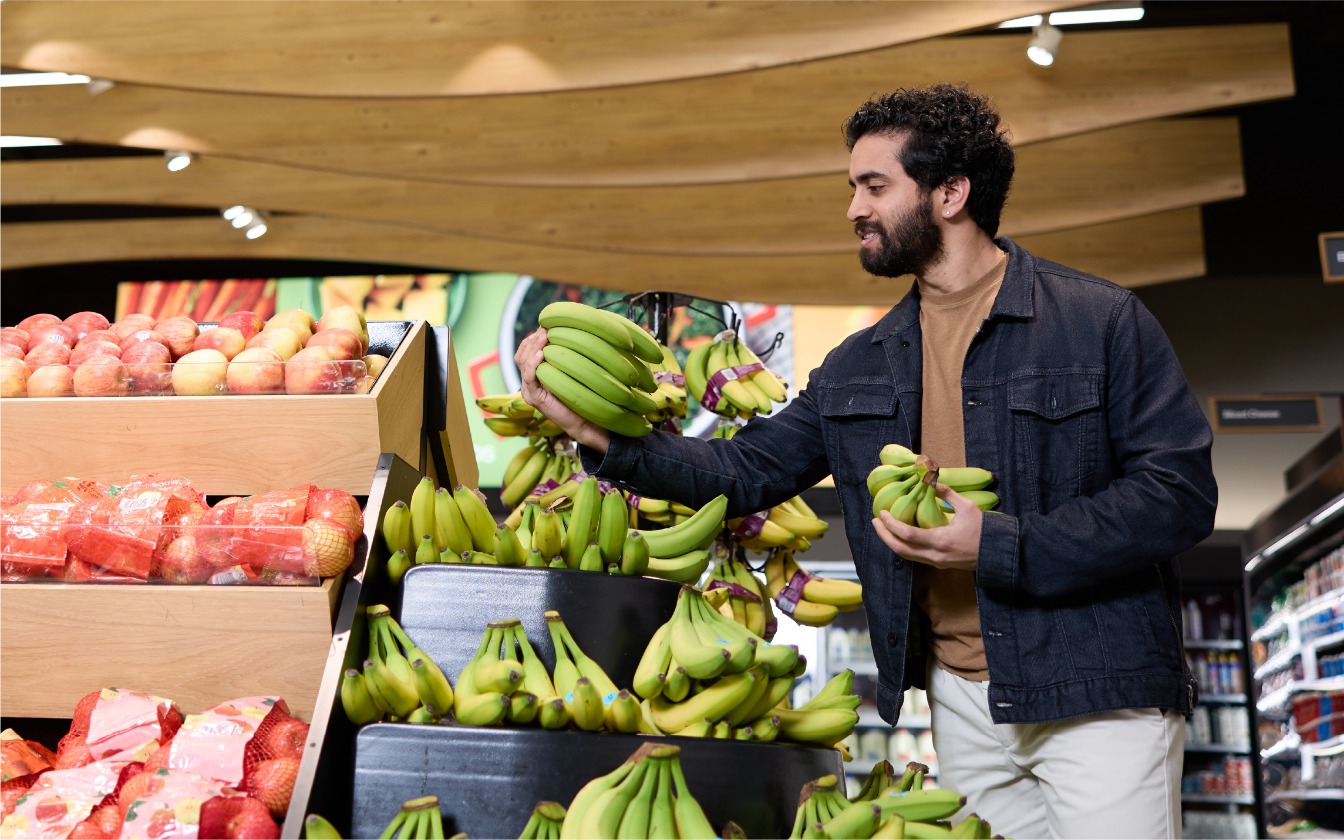 A guest picks up a bunch of bananas inside a Target store.