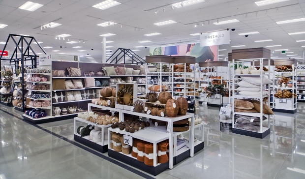 Pumpkin-shared décor items made of wicker and autumnal throw blankets on white retail display shelving.