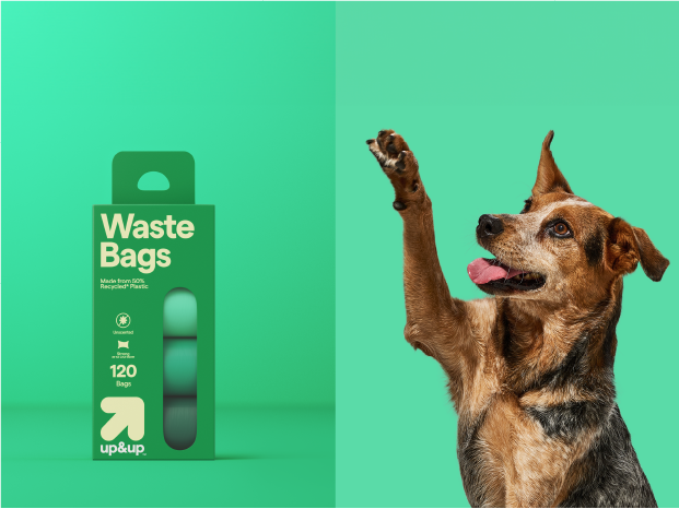 A package of up&up pet waste bags next to a dog with paw in the air.