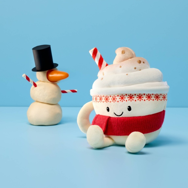 A plush shaped like a warm mug of hot chocolate topped with fluffy whipped cream and red and white striped straw.