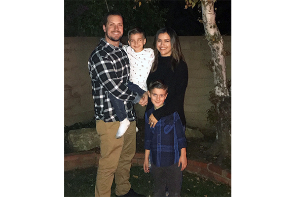 Casey and his family, including partner and two sons, stand in their backyard