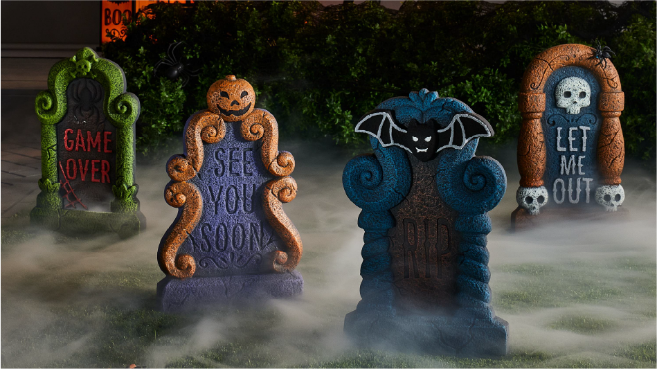 A yard with four tombstone Halloween decorations.