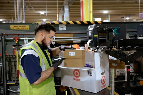 A team member wearing a vest scans the label on a boxed package.