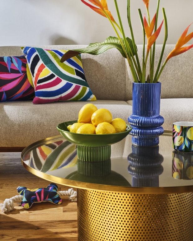 a bowl of lemons and a vase of flowers on a table