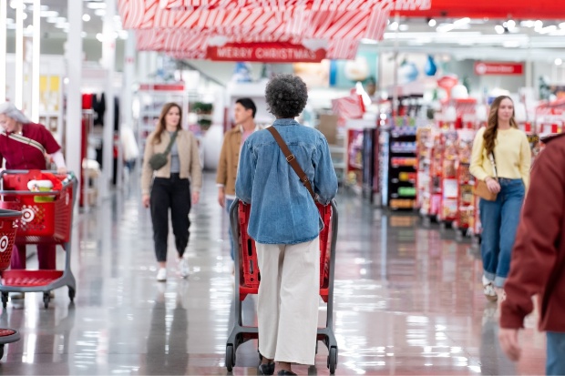 A shopper is pushing a Target cart down a store aisle.