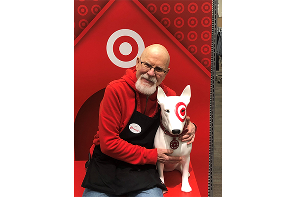 Vyto sits with his arm around a statue of Target mascot Bullseye the dog