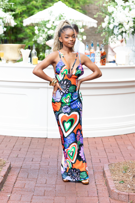 A person poses outdoors in a colorful dress.