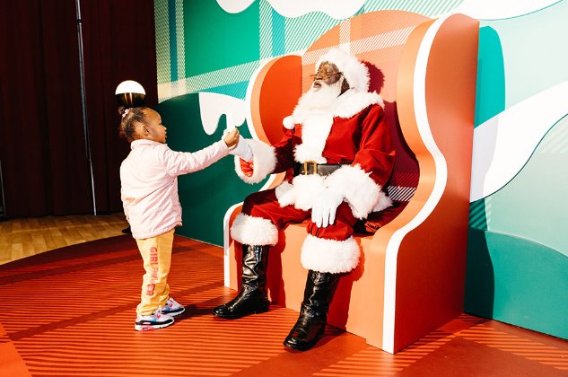 a child standing next to a person in a santa garment