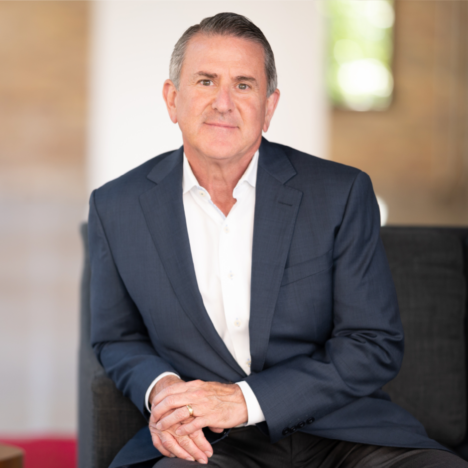 Brian Cornell sitting on a couch next to a table with a plant.