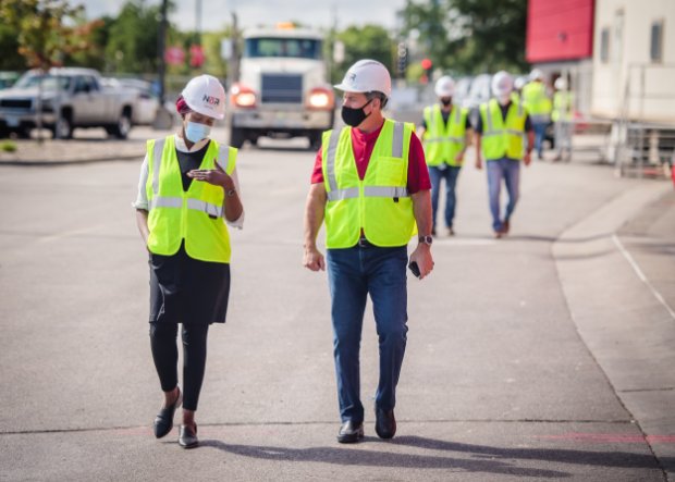 a couple of men wearing safety vests and standing on a street