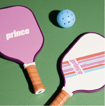 Two pickleball paddles and a light blue pickleball.