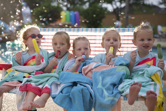 The girls enjoy popsicles as they share a foldable bench chair