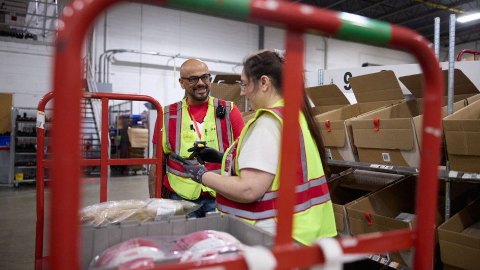 Two Target team members in safety vests talking on the floor of a Supply Chain facility.