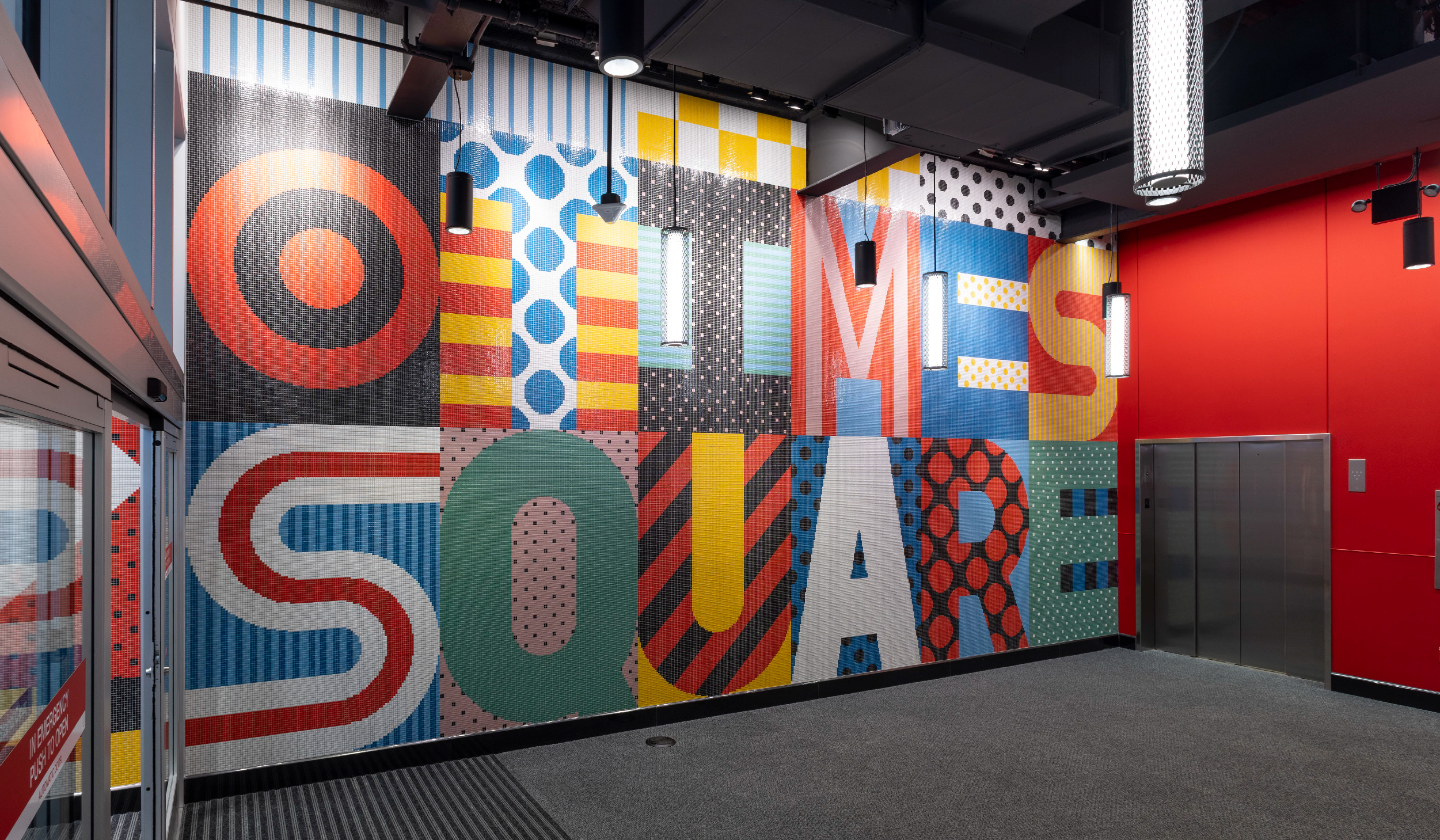 Multicolored tiles spell out “Times Square” on a large wall.