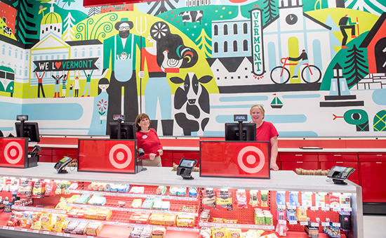 Two team members staff cash registers in front of a giant mural