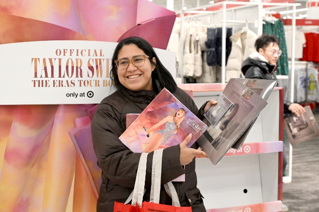 A smiling fan shows off their “Taylor Swift | The Eras Tour Book” and “The Tortured Poets Department: The Anthology” vinyl at a New Jersey Target store on Black Friday