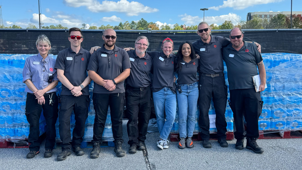 Target team members smile for a photo in front of cases of water.