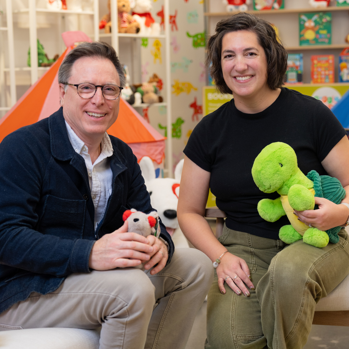 Jeff Carter and Ellen Rizzardi sit, holding Gigglescape plush toys.