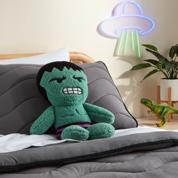 A gray bed displays a Marvel Hulk plush doll.