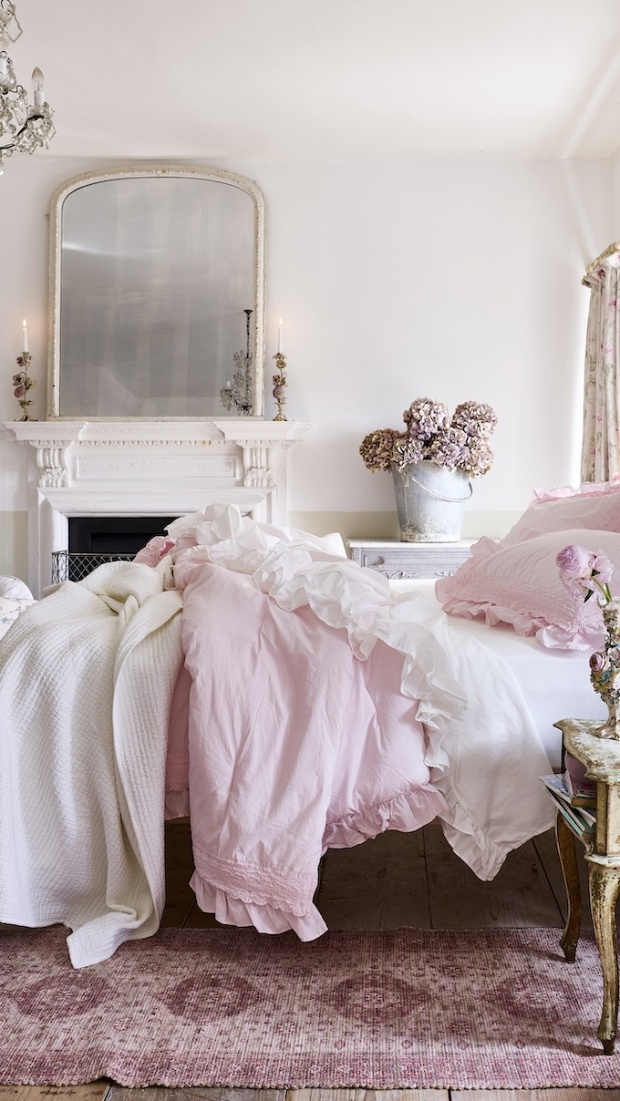 White and light pink ruffled bedding in room decorated with vintage furniture