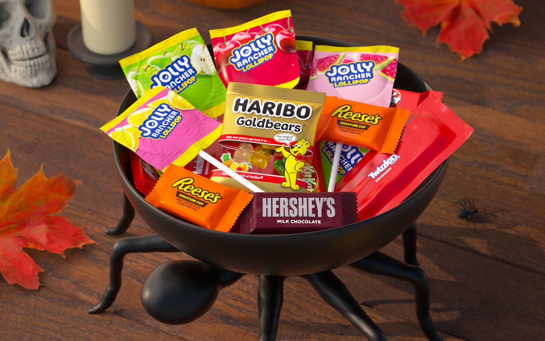 A black bowl that looks like a spider is filled with trick-or-treat candy.