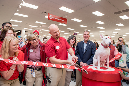 The store team leader, governor and several team members stand next to Bullseye the dog and cut the ribbon to open the store
