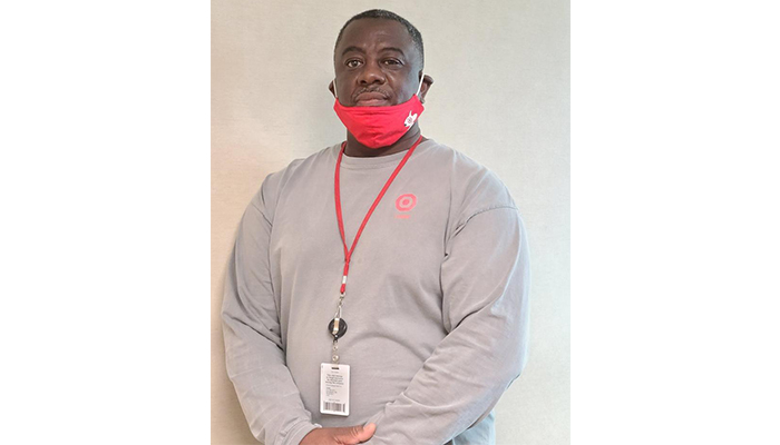 A head-and-shoulders shot of Calvin, wearing a gray shirt, red face mask and Target lanyard