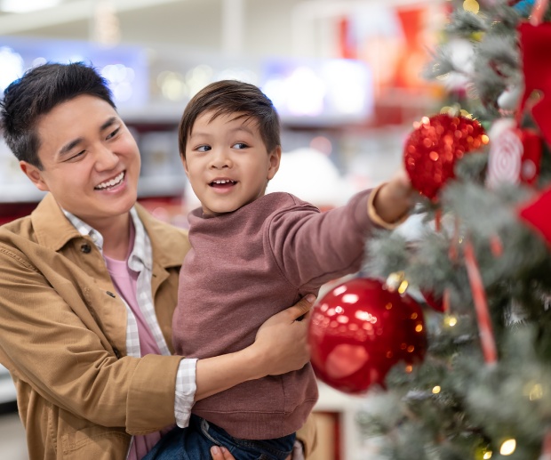 A guest holding a child stands next to a Christmas tree in a Target store.