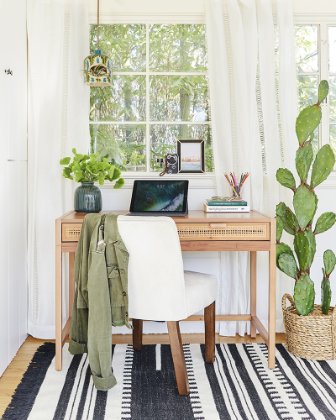 a desk with a chair and a window with plants