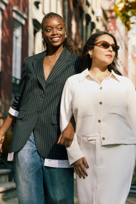Two models walk down the street in a city