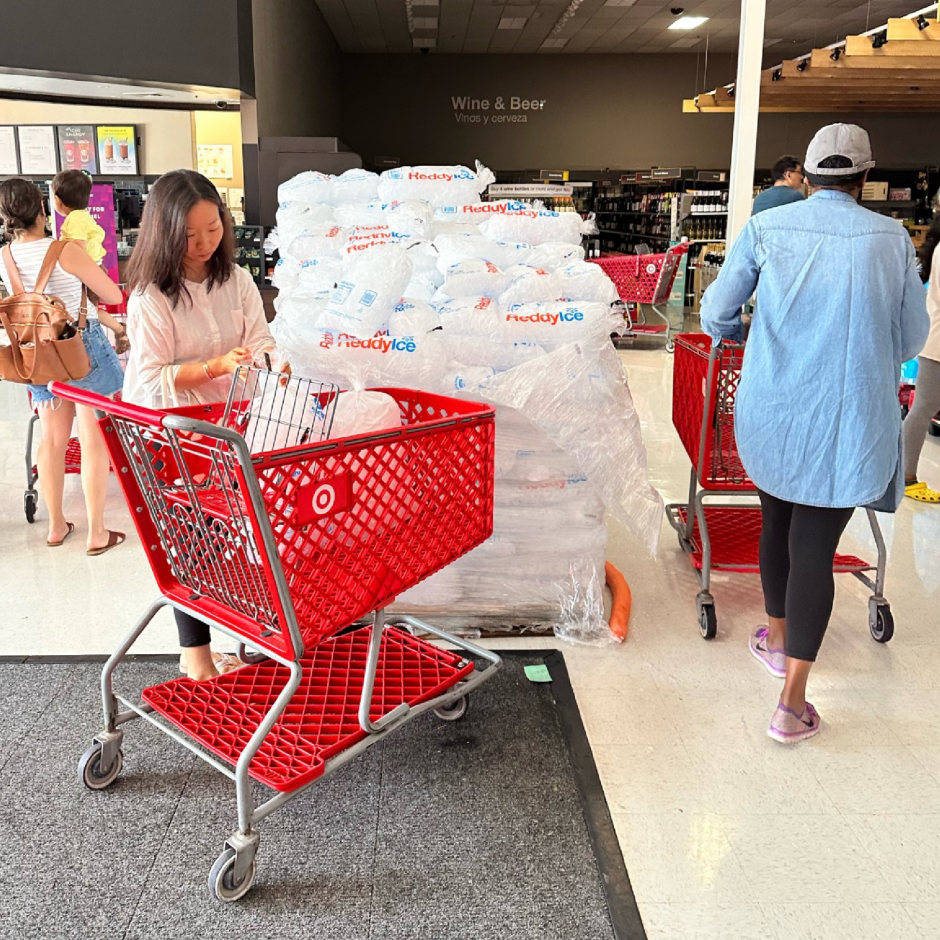 A Target guest next to a pile of bags of ice and a Target cart with bags of ice.