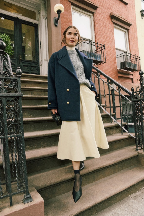 a person in a trench coat and boots standing on a staircase