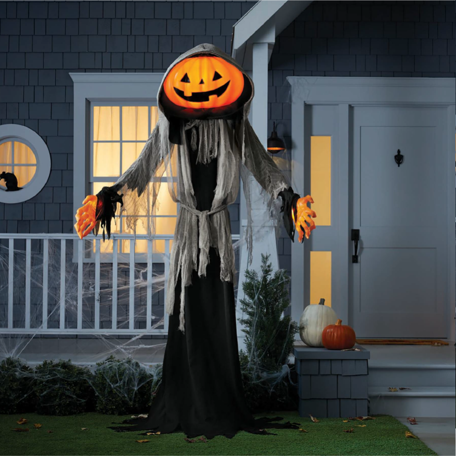 A grinning Lewis the Halloween Ghoul stands in front of a house.