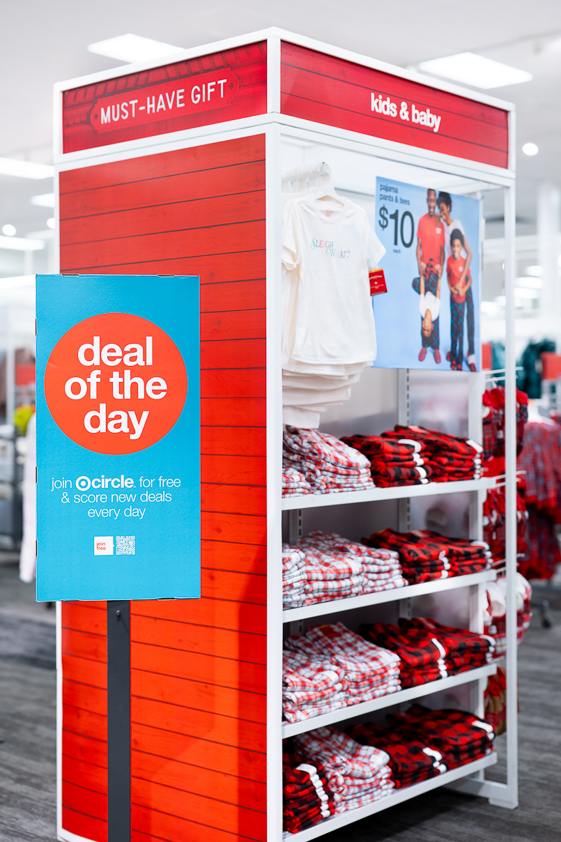 A Deal of the Day sign is posted next to a display of must-have gifts for kids and baby. apparel.