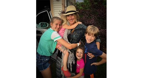 Rachel hugs her four kids in front of their house