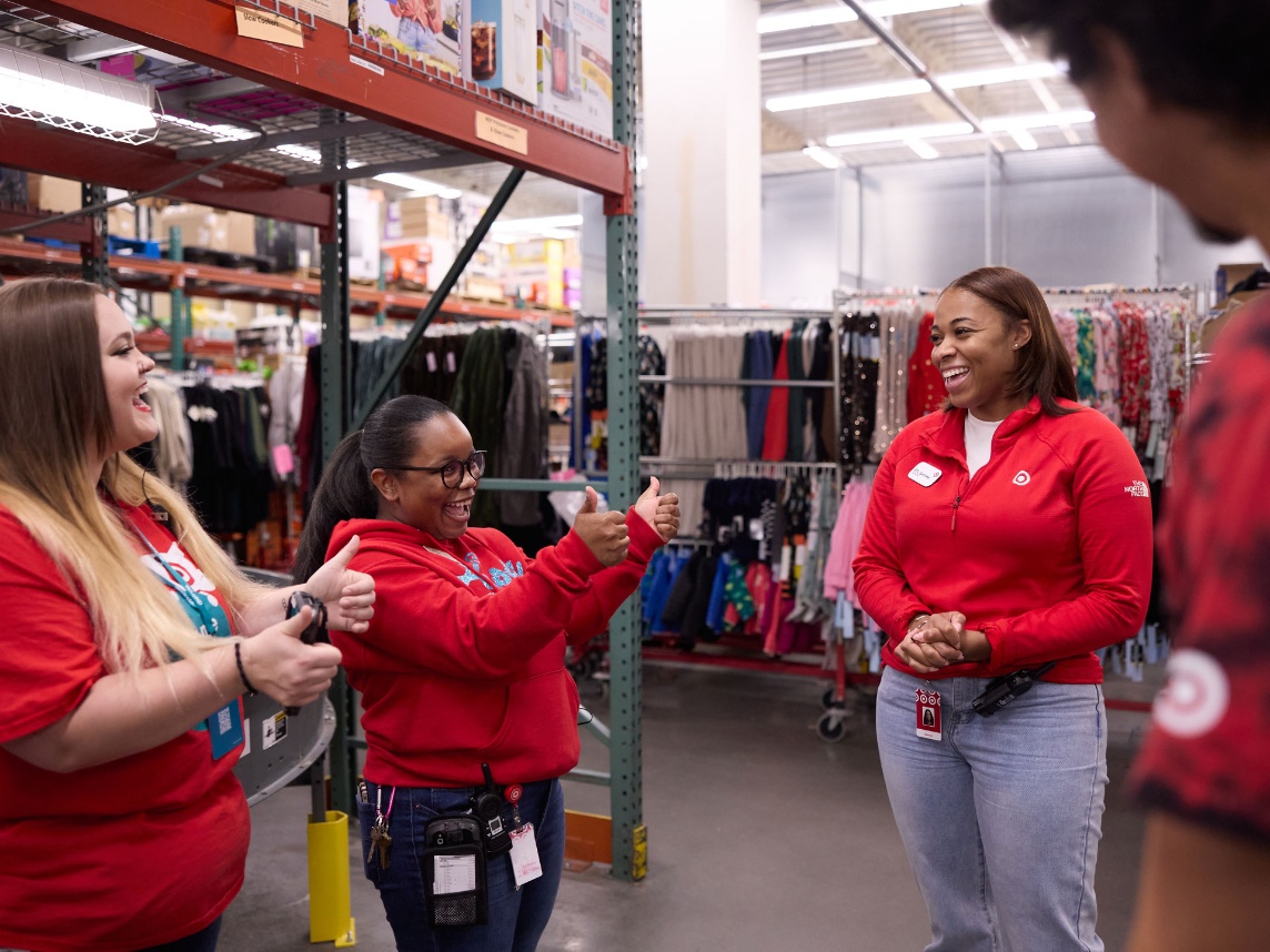 A group of Target team members giving each other a thumbs up as they huddle in the back of the store.