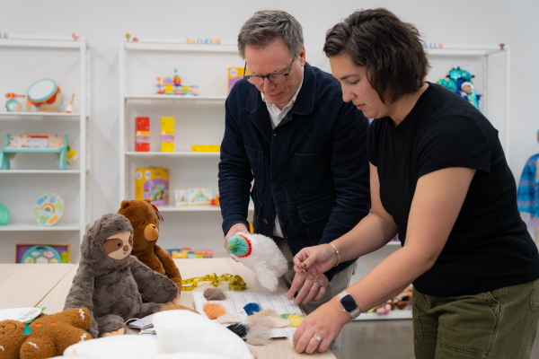 Jeff Carter and Ellen Rizzardi stand at a table looking at Gigglescape plush toys