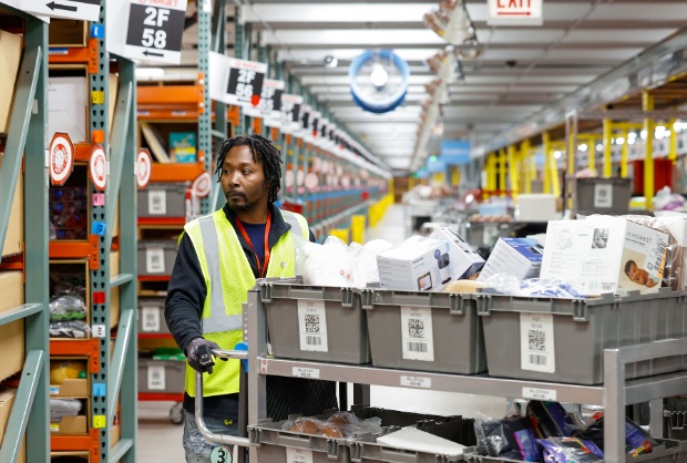 A team member at a warehouse moves a cart holding bins of guest items.