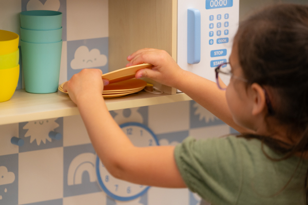 a little girl taking a pretend dish off of a shelf