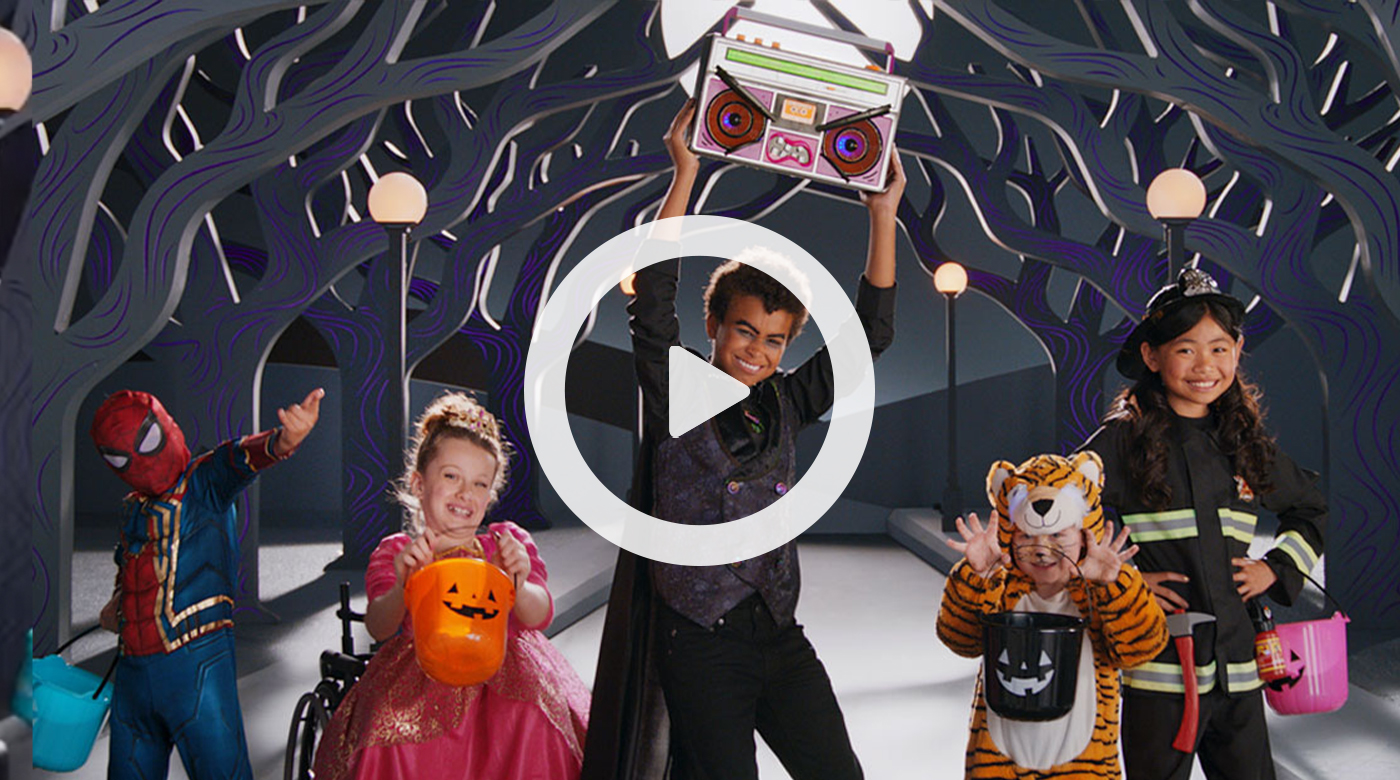 A group of kids in costumes, including a vampire holding a boom box, get ready to dance