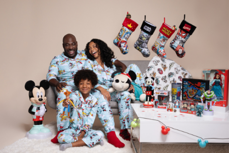 A family sitting together in matching Disney pajamas, surrounded by toys and stockings.
