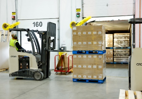 A team member driving a forklift picks up a pallet of boxes.