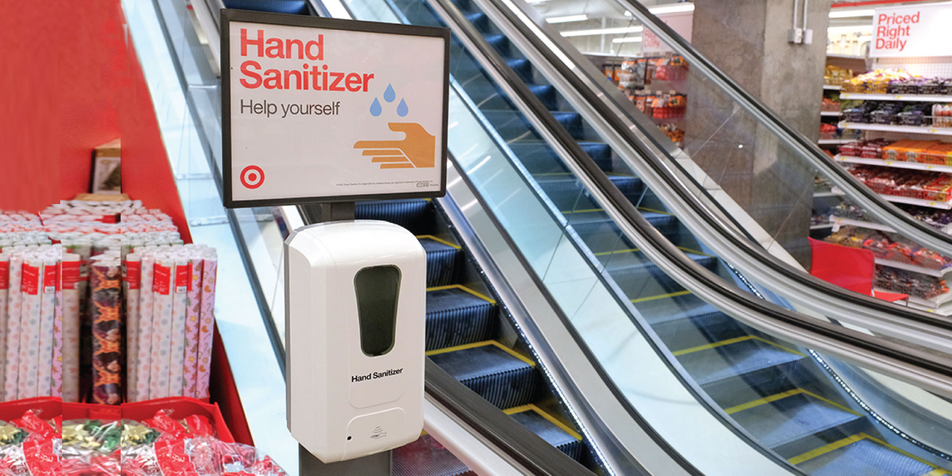 A hand sanitizing station is shown in a Target store with escalators in the background