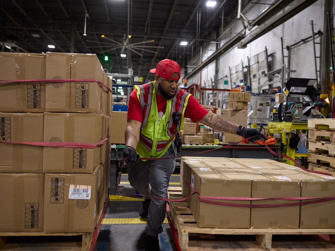 A Target team member in a safety vest gets boxes ready to move in a supply chain facility.