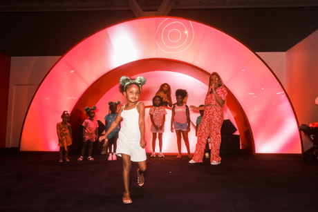 A child walks down a runway with a small group of people and the Bullseye logo in the background.