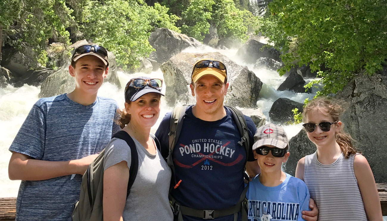 Nick smiles with his family in front of a waterfall