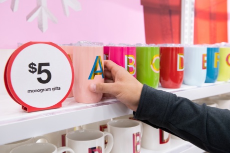 A guest reaches for a mug emblazoned with the letter A, next to a $5 sign.
